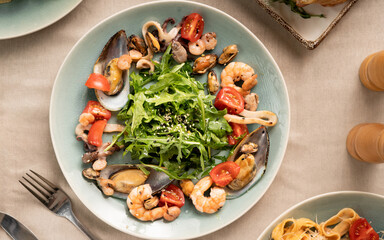 Mix salad with seafood shrimp, squid and arugula on a light background. Top view.