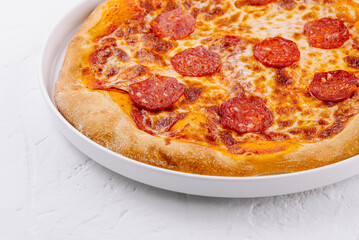 Freshly baked pepperoni pizza on white plate