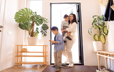 A happy Asian family. A young attractive woman helps to take off her little daughter shoes