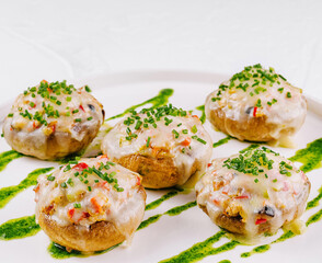 Gourmet stuffed mushrooms on plate with pesto drizzle
