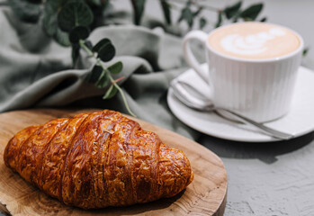 Fresh croissant and latte on rustic table