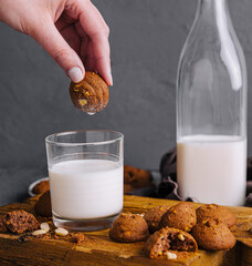 Hand dipping cookie in milk glass