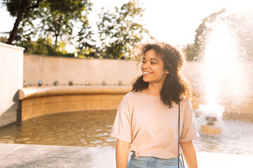Portrait of a charming mixed-race teenager in casual clothes walking in a park. A pretty smiling...