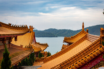 Toits de temple d'architecture chinoise, aux briques oranges, faisant face à un lac et un ciel...