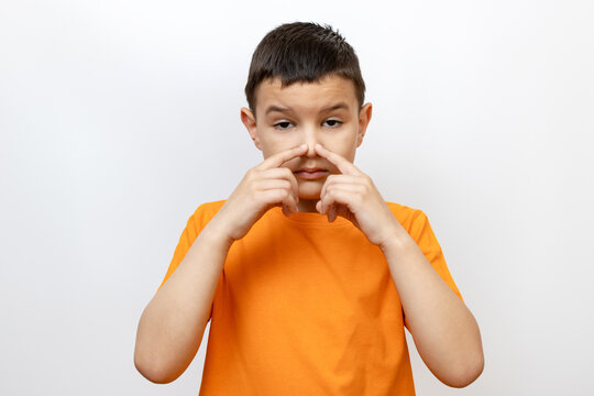 The boy touches his nose with his fingers. Sincere children's emotions.