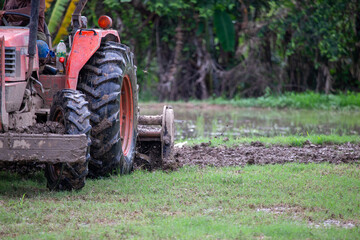 selective tractor plowing soil in rice fields It's about to be rice planting season in the rice fields. It's almost rainy season in the rice fields of
