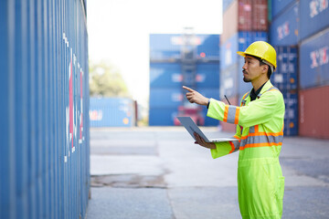 worker or engineer using laptop computer and pointing at containers warehouse storage