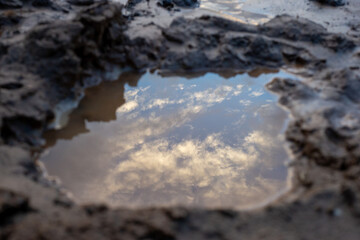 Selective focus, reflection of the sky and clouds in the water hole