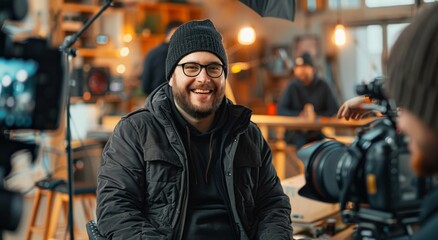 Smiling bearded man in black winter jacket during video production in cozy cafe