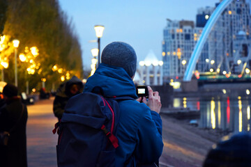 The center of the night city of Astana, illuminated by the light of houses and lanterns. Kazakhstan, Asia. High-rise buildings. People at the bridge.