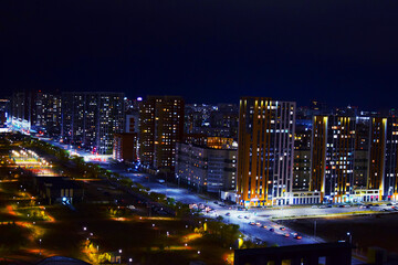 Fototapeta premium The center of the night city of Astana, illuminated by the light of houses, lanterns and car headlights. Kazakhstan, Asia. High-rise buildings.