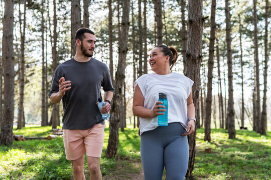 An inspiring scene unfolds as a beautiful, overweight female embarks on a jog in the park with her dedicated partner, embracing their journey to better health.	 