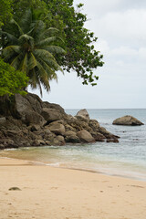 Granite stones and trees near white sandy beach of top soilei, Calm sea, Mahe Seychelles