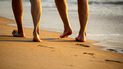 people walking barefoot on the sandy beach at sunset