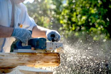 a carpenter works with an electric pipe on a sunny day