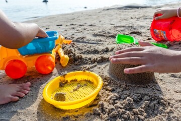 Children playing in the sand on the beach with plastic beach toys