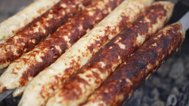Grilled lula kebab on skewer on grill, close-up. Delicious homemade sausages