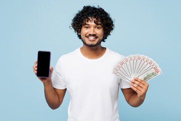 Young happy Indian man wear white t-shirt casual clothes hold fan of cash money in dollar banknotes...