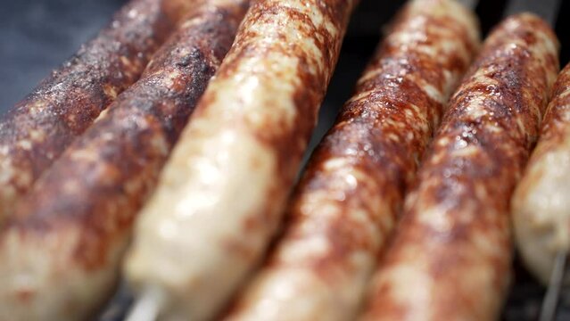 Grilled lula kebab on skewer on grill, close-up. Delicious homemade sausages