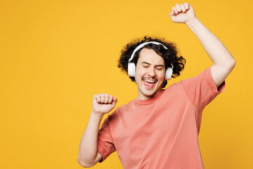 Young smiling cheerful fun happy man he wearing pink t-shirt casual clothes listen to music in...
