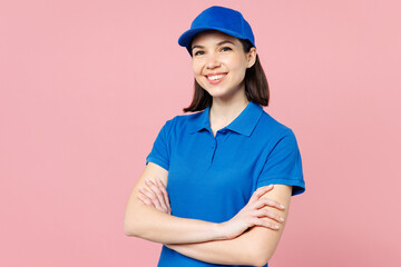 Professional happy delivery girl employee woman wear blue cap t-shirt uniform workwear work as dealer courier hold hands crossed folded isolated on plain pastel pink background studio Service concept