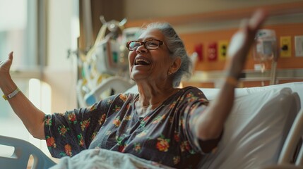 Obraz premium Portrait of a happy elderly woman sitting in a hospital room and raising her hands up.