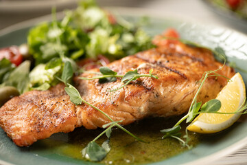 Close-up of grilled salmon fillet served with vegetables and sauce