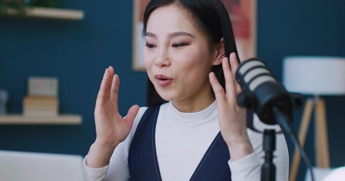 Young Asian teacher starting online class. Working remotely. Using professional microphone setup for better sound quality. Greeting with students by waving hands. Using video for remote teaching.