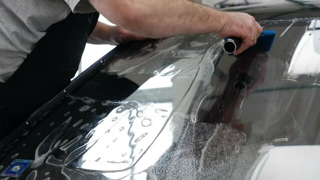 Applying tinting foil on a car window	

