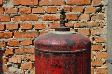 Obraz premium old gas cylinder near a brick wall