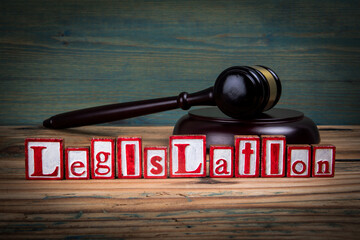 LEGISLATION. Red alphabet letters and judge's gavel on wooden background. Laws and justice concept