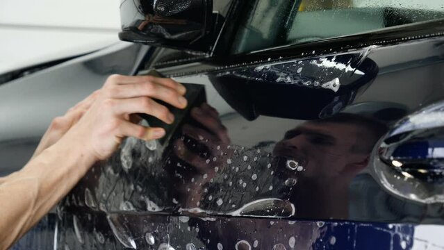 Close up of paint protection film installation on front bumper of modern luxury car. PPF is polyurethane film applied to car surface to protect the paint from stone chips, bug splatter, and abrasion.