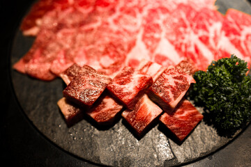 meticulously cut and well-arranged beef with premium marbling alongside fresh green herbs