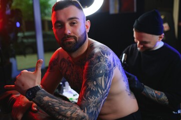 Tattooing. Man creating a picture on his back by a professional tattoo artist