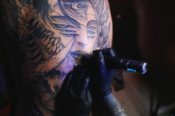 Shot of a tattoo artist hands forming perfect lines on man back with ink