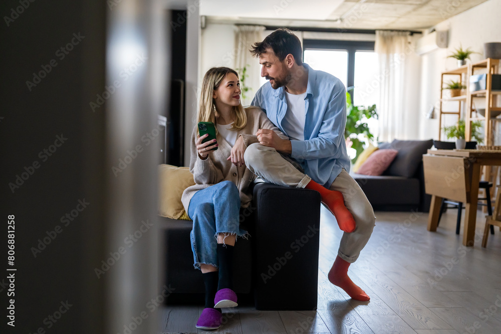 Wall mural Happy young couple, woman and man hugging, using smartphone together. Social media concept.