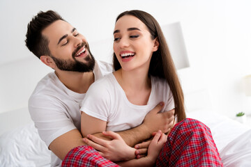 Photo of positive cheerful couple in morning guy cuddle laughing girl in weekend house indoors