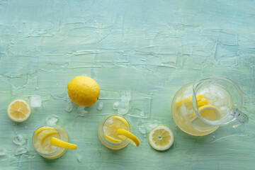 Lemonade. Lemon water drink with ice. Two glasses and a pitcher on a blue background, shot from the...