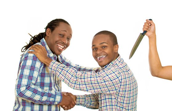 Fake friend backstabbing concept. Portrait hypocrite, crafty man gives handshake to a guy at same time trying to stab him in back with knife isolated white background. 