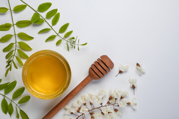 Raw organic acacia flowers honey jar with dipper and acacia flowers. Fresh honey top view, flat lay. Space for text.