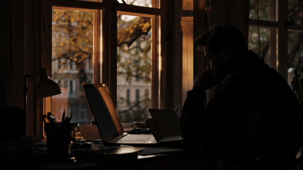 The quiet concentration of a man working from home as daylight wanes and evening beckons.