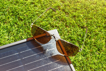 The alternative energy generation with solar panel. The set of solar panel an sunglasses on the green grass background. - 806905251