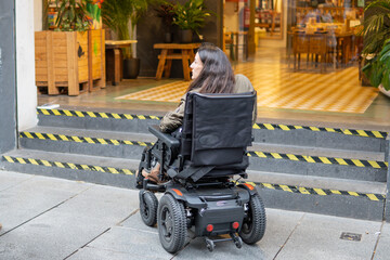restricted wheelchair access to a municipal market. Woman in electric wheelchair with gesture of...