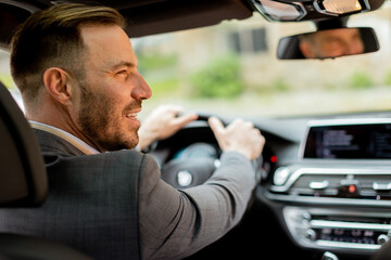 Smiling man enjoying a sunny drive in a modern car interior