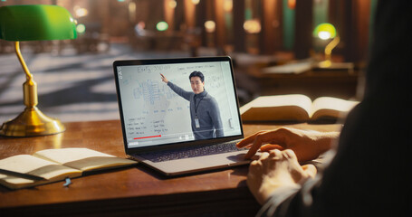 Asian Male Professional Presenting a Business Strategy on a Laptop Screen, Surrounded by Books in a...