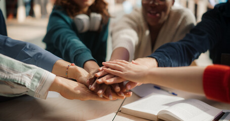 Diverse Group of Students Collaborating in a Library, Hands Joined in Unity. Multiethnic Teamwork...