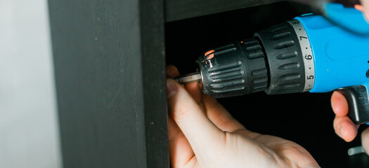 Banner Master uses a cordless screwdriver to screw shelf close up - home improvement concept. Copy...