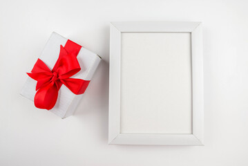 Top view photo of gift box and white wooden frame with empty space.