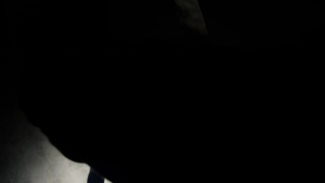 a fighter wraps bandages on his hands in the dark. top view