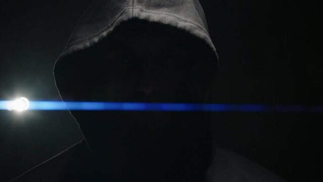 silhouette of a man in a hood with a closed face in the backlight. anamorphic lens